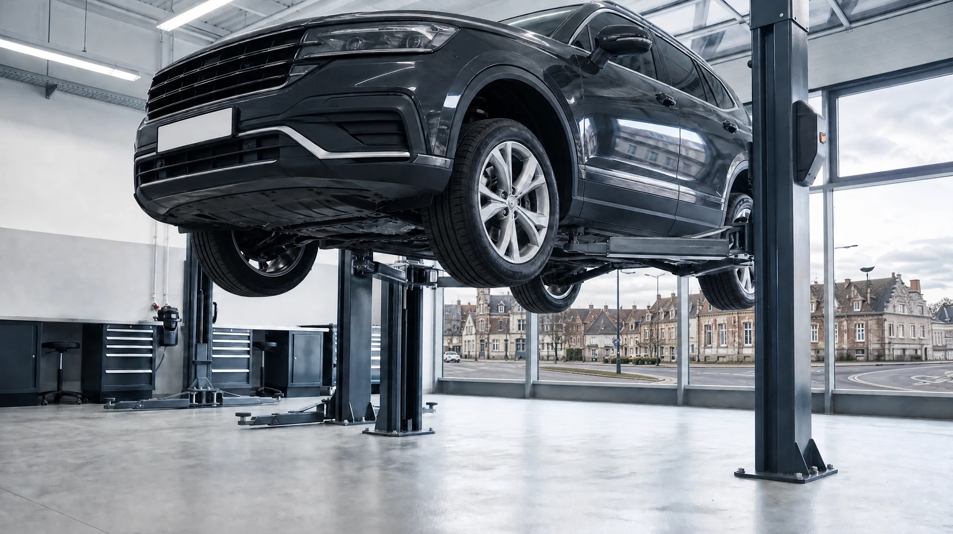 Mécanicien automobile en combinaison bleue inspectant le dessous d'un véhicule surélevé dans un garage professionnel
