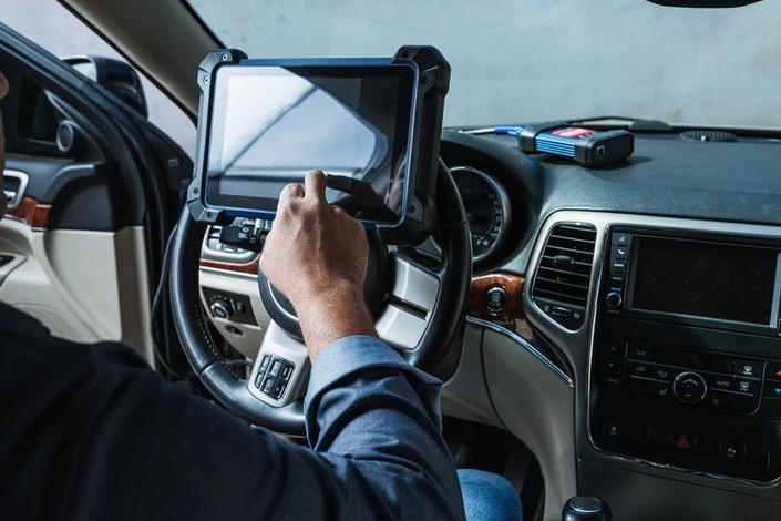 Mécanicien automobile en combinaison bleue effectuant un contrôle technique sur véhicule surélevé dans garage professionnel